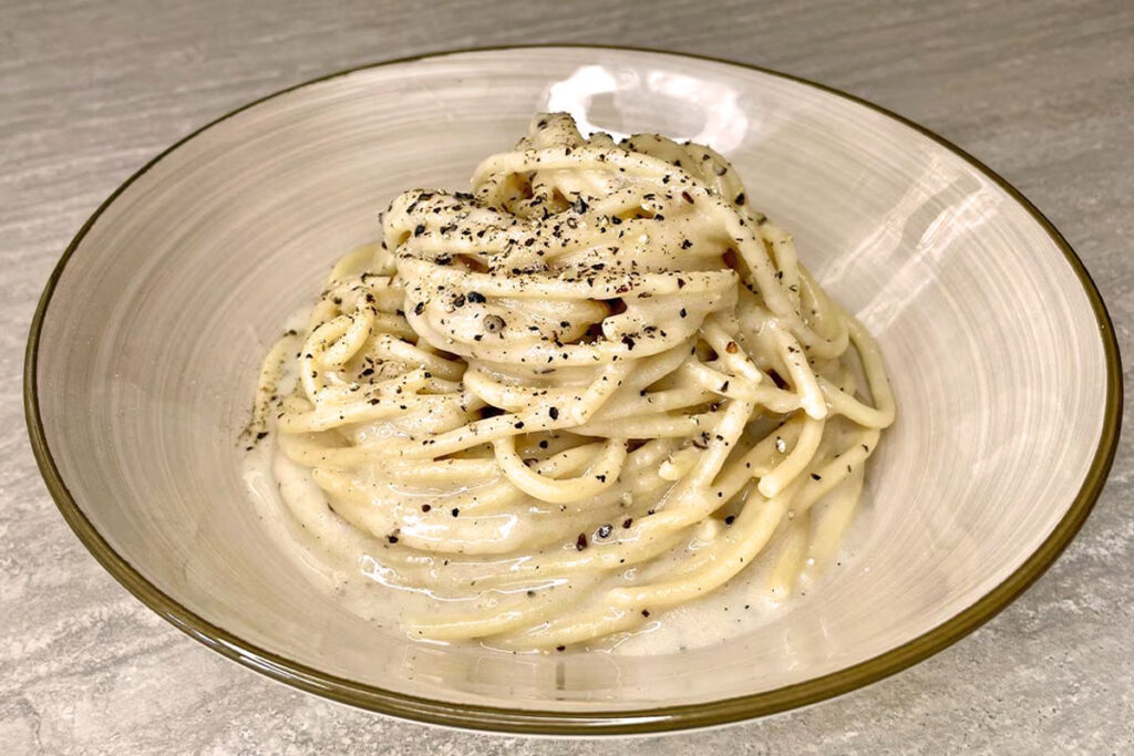 Teller Spaghetti Cacio e Pepe mit cremiger Pecorino-Romano-Soße und frisch gemahlenem Pfeffer – klassisches römisches Pasta-Gericht mit intensiven Aromen.