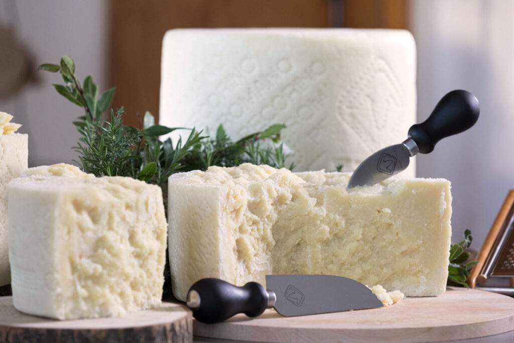 Frisch aufgebrochene Pecorino-Romano-Stücke mit Käsemessern und Kräuterdeko – servierbereit für Antipasti oder rustikale Verkostung.