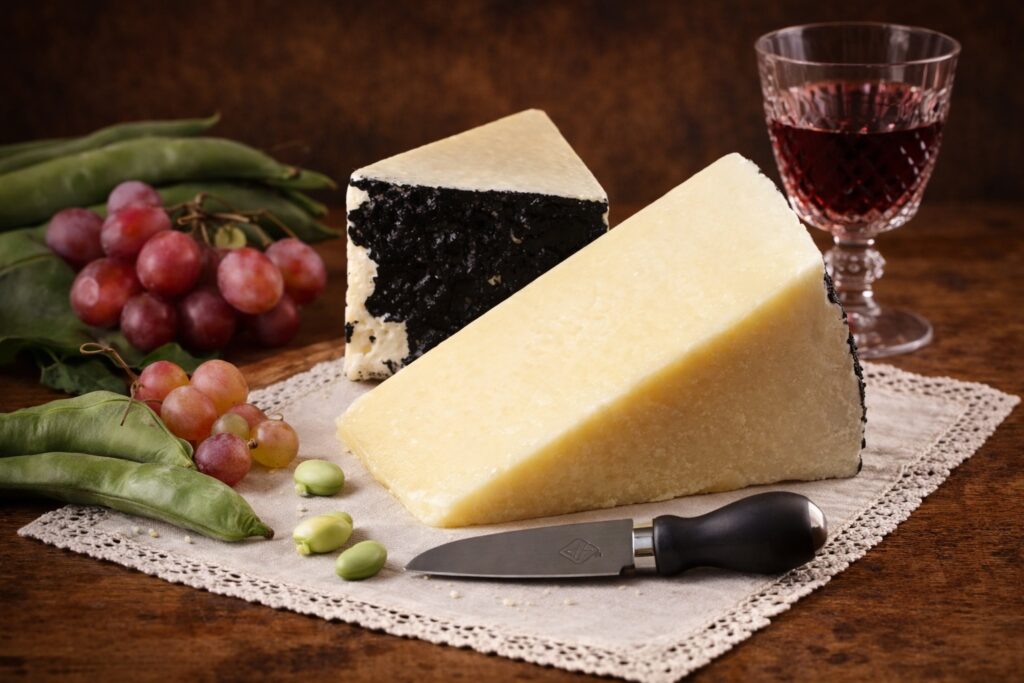 Pecorino Romano mit schwarzer Rinde, Favabohnen und roten Trauben – italienischer Hartkäse auf Leinentuch, ideal zu Wein und Antipasti.