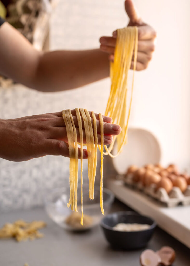 Frisch geschnittene Tagliatelle werden sorgfältig mit den Händen zu Portionen vorbereitet – hausgemachte Pasta auf höchstem Niveau.