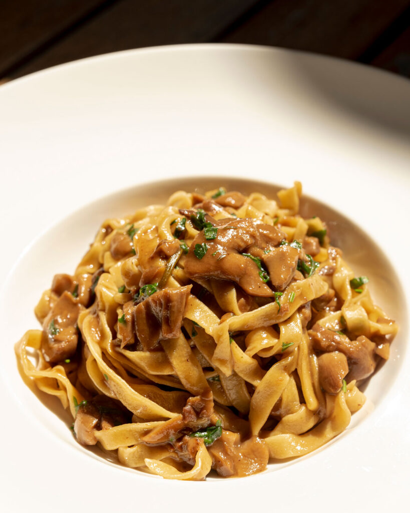 Cremige Tagliatelle ai Funghi Porcini serviert in einem eleganten weißen Teller – intensiver Pilzgeschmack trifft handgemachte Pasta.