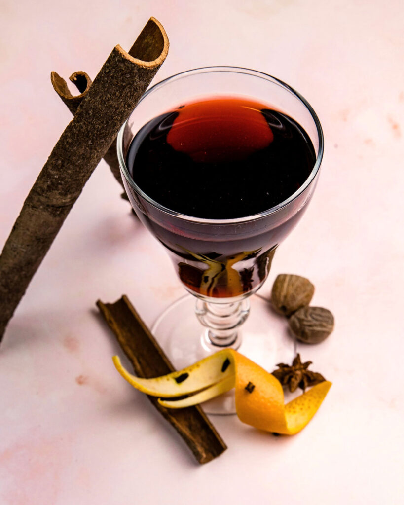 Elegantes Glas Vin Brulé mit Gewürzen wie Zimt, Muskatnuss, Sternanis und Orangenschale