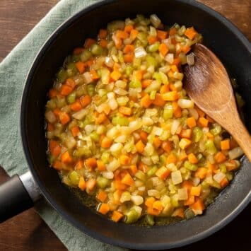 Italienisches Soffritto in der Pfanne – Zwiebel, Sellerie und Karotte werden langsam in Olivenöl gegart, die klassische Geschmacksbasis der italienischen Küche.