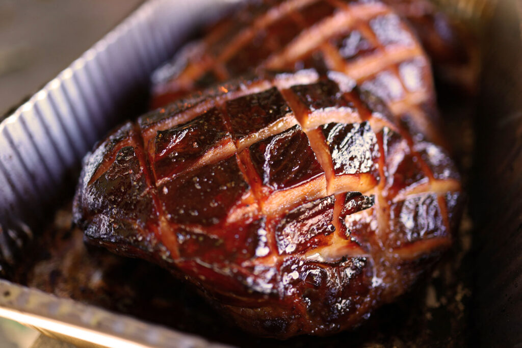 Knusprig gebratener Schweinebraten mit karamellisierter Kruste direkt aus dem Ofen in Aluschale.