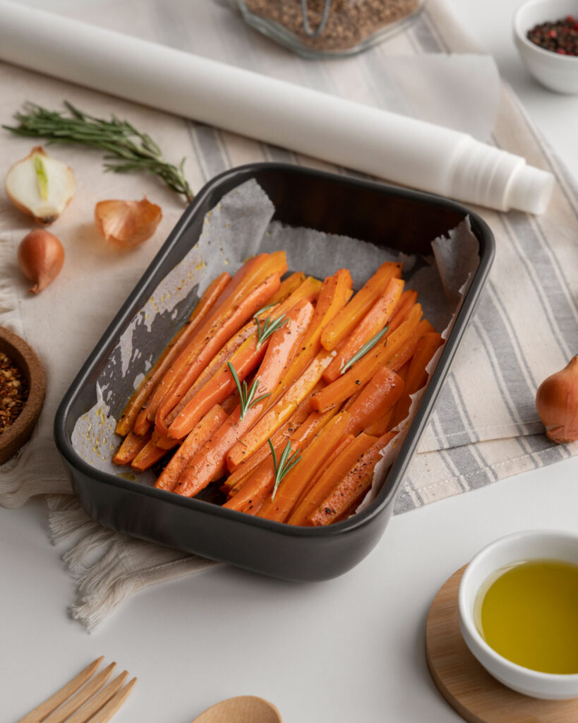 In Streifen geschnittene Karotten mit Rosmarin in einer ofenfesten Form, bereit zum Garen in der Heißluftfritteuse