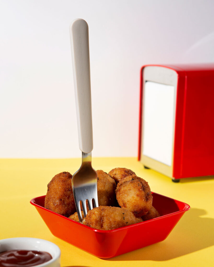 Goldbraune frittierte Snacks in einer roten Schale mit Gabel – servierbereit als knuspriger Genuss aus der Heißluftfritteuse