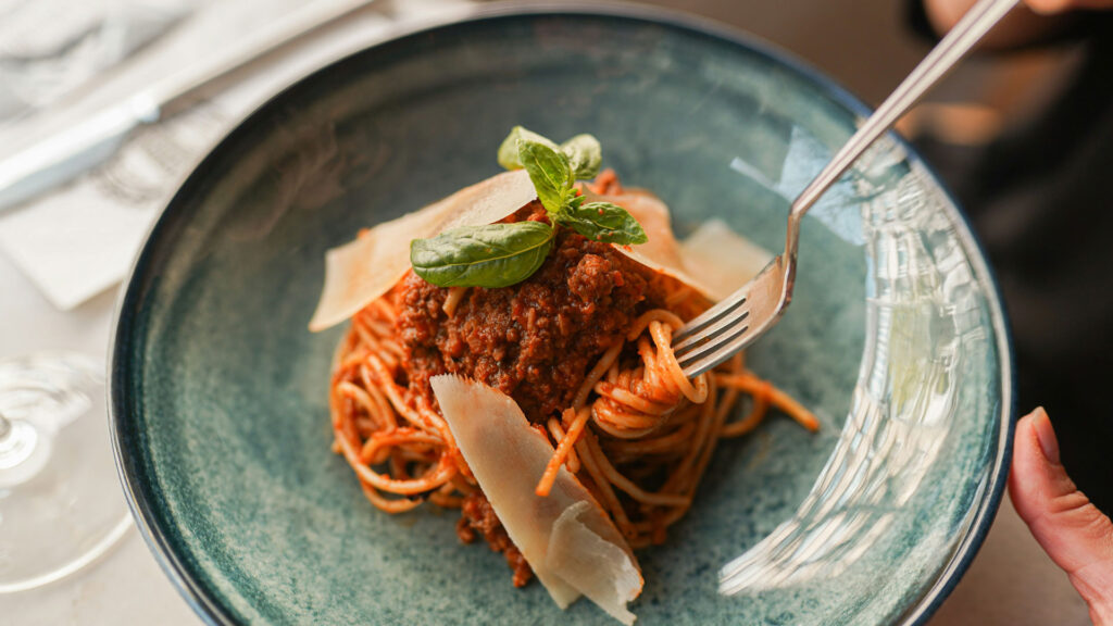 Spaghetti alla Bolognese mit frischem Basilikum und Parmesanspänen – Klassiker der italienischen Küche und weltbekanntes Symbol kulinarischer Identität Italiens
