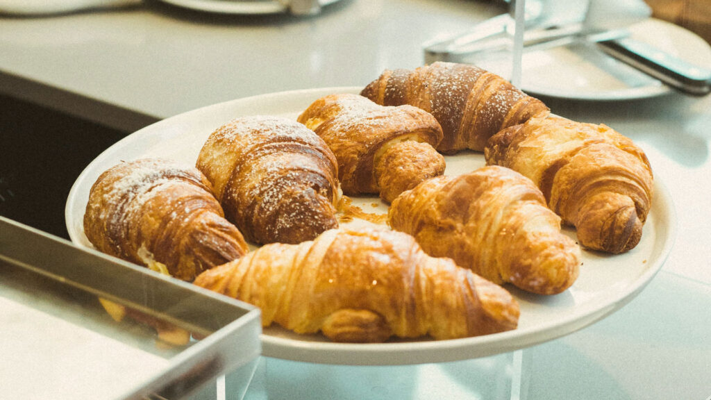 Goldbraune italienische Cornetti mit Puderzucker – beliebtes Frühstücksgebäck und fester Bestandteil der Dolce-Vita-Kultur Italiens