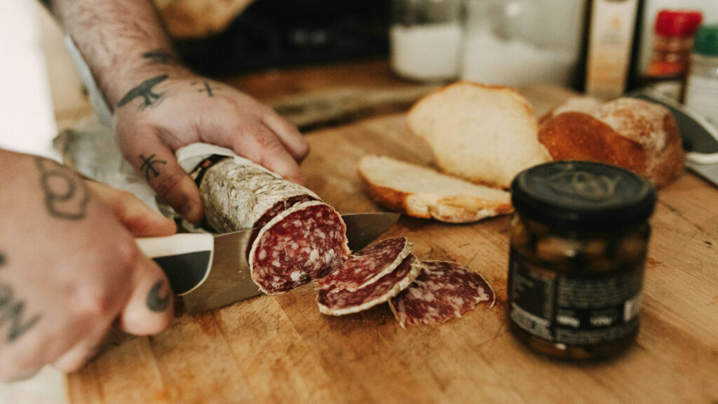 Traditionelle italienische Salami, frisch aufgeschnitten auf Holzbrett mit Landbrot und Antipasti – Ausdruck regionaler Wurstkunst und kulinarischer Vielfalt