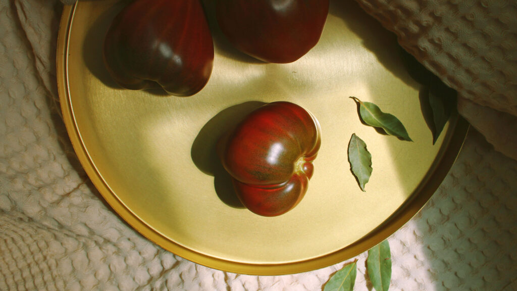 Italienische Ochsenherztomate auf stilvoller goldener Platte mit Lorbeer – Hommage an die Qualität der italienischen Zutatenküche