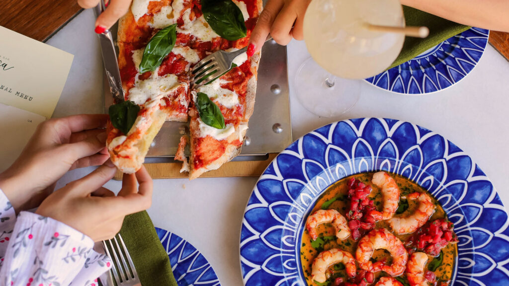 Gemeinsames Genießen von Pizza Margherita und Meeresfrüchten – gelebte italienische Esskultur am Tisch