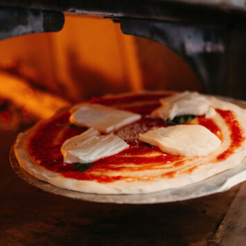 Traditionelle Zubereitung einer Pizza im Steinofen – Herzstück der neapolitanischen Küche und UNESCO-Weltkulturerbe