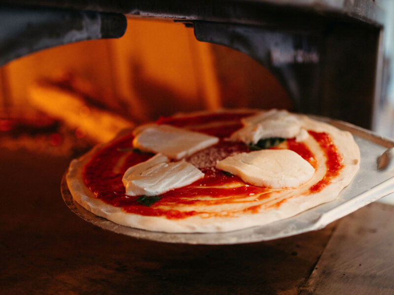 Traditionelle Zubereitung einer Pizza im Steinofen – Herzstück der neapolitanischen Küche und UNESCO-Weltkulturerbe