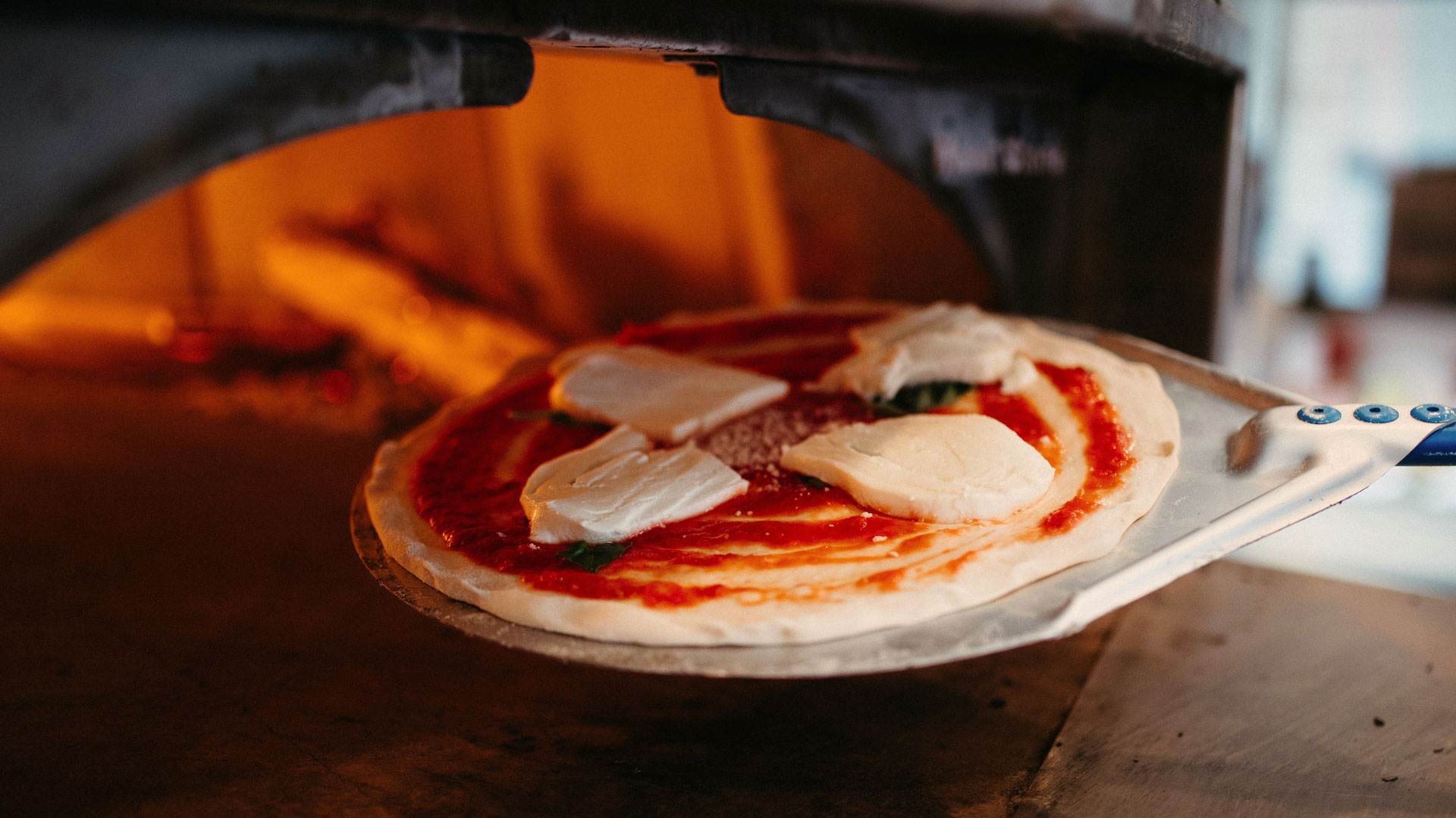 Traditionelle Zubereitung einer Pizza im Steinofen – Herzstück der neapolitanischen Küche und UNESCO-Weltkulturerbe