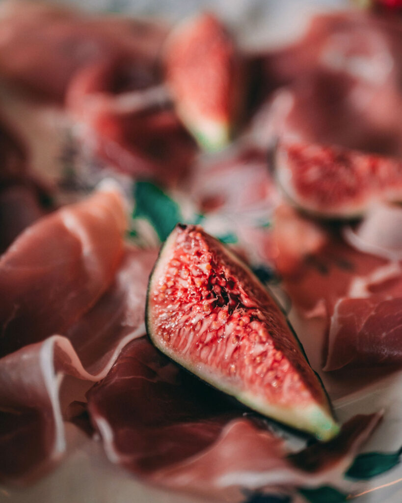Detailaufnahme von Prosciutto Crudo mit frischer Feige – hauchdünn geschnittener italienischer Rohschinken in Nahaufnahme.