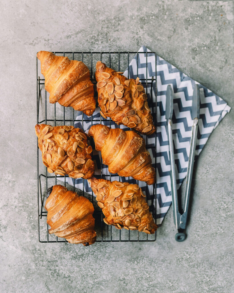 Hausgemachte Cornetti mit Mandeln auf Gitter – italienisches Frühstücksgebäck aus der Bäckerei.