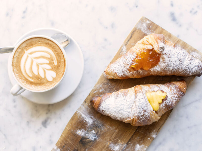 Italienisches Frühstück mit Cornetti und Cappuccino – Cornetto mit Marmelade und Vanillecreme als typische Frühstückskultur in Italien