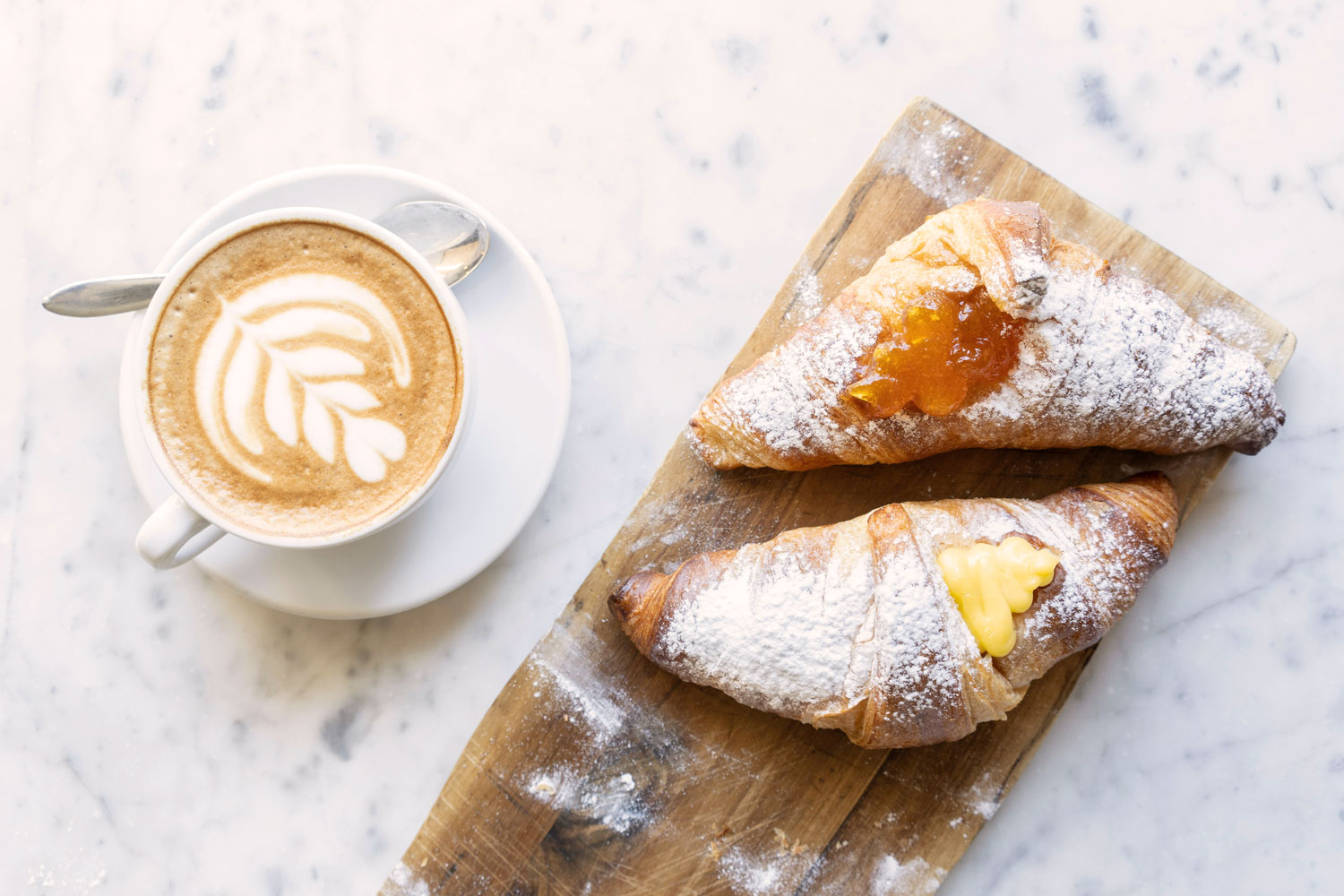 Italienisches Frühstück mit Cornetti und Cappuccino – Cornetto mit Marmelade und Vanillecreme als typische Frühstückskultur in Italien