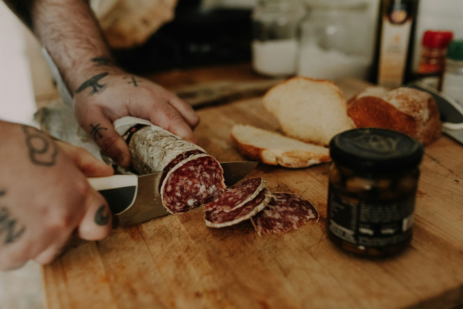 Handwerkliche Herstellung von Salame – italienische Rohwurst wird frisch geschnitten und mit Brot serviert