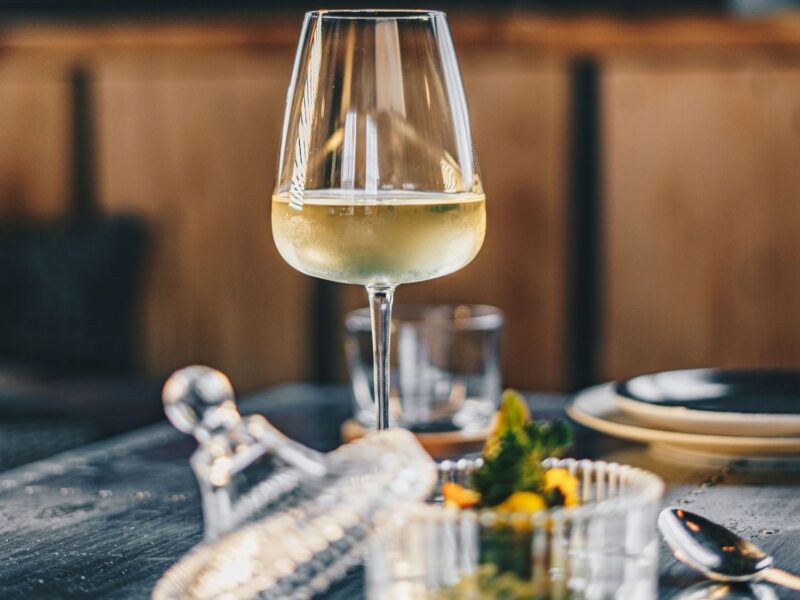 Glas Weißburgunder auf gedecktem Tisch im Restaurant – stilvolle Präsentation eines eleganten Weißweins.