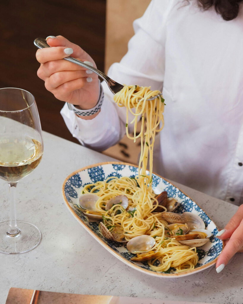 Spaghetti alle Vongole genießen mit Weißwein – authentisches italienisches Essen mit Meeresfrüchten und Pasta