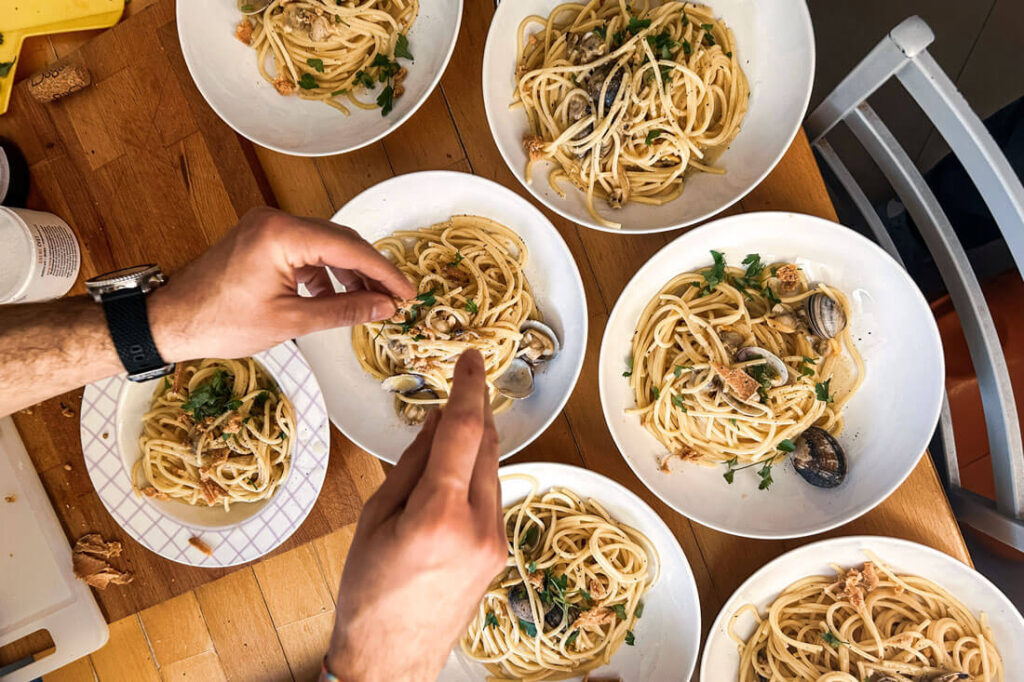 Spaghetti alle Vongole Zubereitung – mehrere Teller mit italienischer Pasta und Venusmuscheln in der Küche