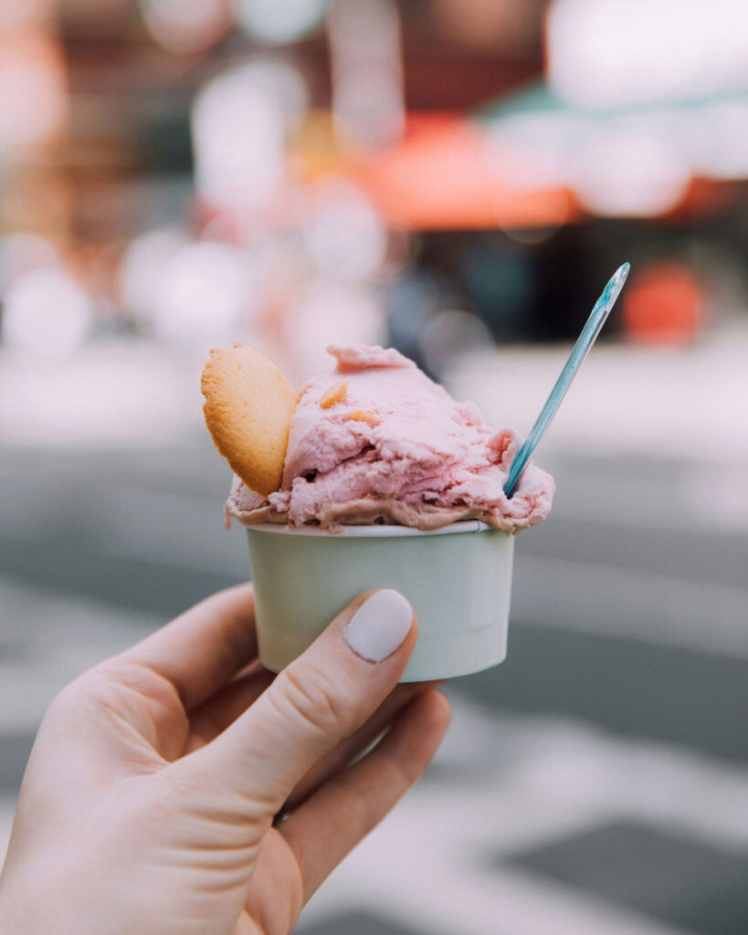 Italienisches Gelato im Becher – cremiges Fruchteis mit Eiswaffel und Löffel aus der Gelateria